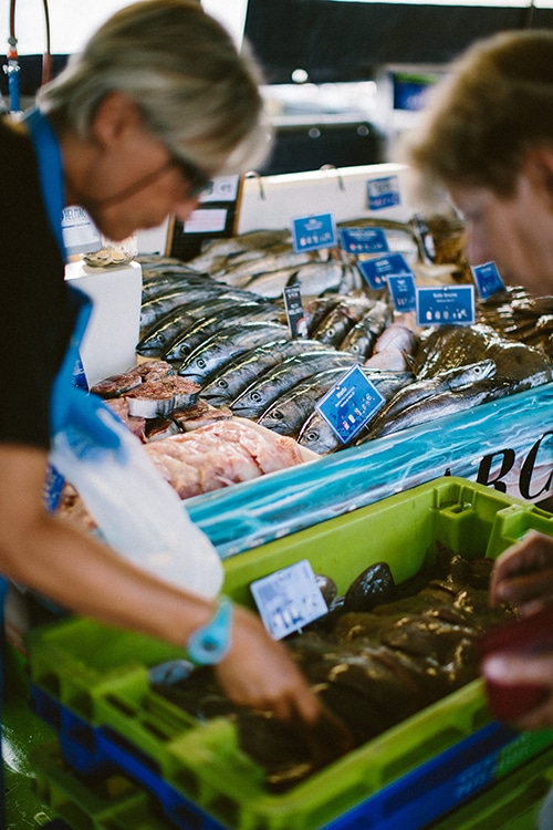 Twee mensen zoeken vis uit op de vismarkt in Capbreton.