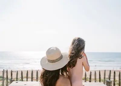 Vrouw met kind kijken uit over de zee vanaf een naturistenstrand aan de Atlantische kust van Frankrijk.