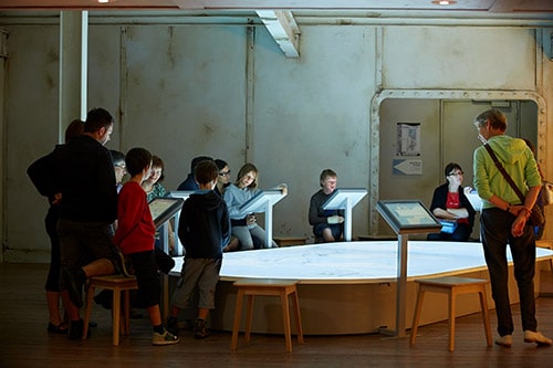 Kinderen en volwassenen bekijk een tentoonstellin g in het museum Escal’Atlantic.